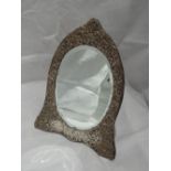 A silver dressing table mirror of arched oval form having moulded scroll decoration and blue