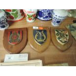 A selection of vintage military and similar shield and crest plaques with hand painted detail,