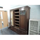 A late Victorian oak wardrobe in the Art Nouveau style having coloured glass panels and copper stra