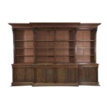 A LARGE GEORGE IV MAHOGANY BREAKFRONT BOOKCASE, with stepped moulded cornice above open shelving,