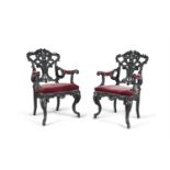 A PAIR OF CARVED EBONISED TIMBER FRAMED ARMCHAIRS, in the George II rococo taste, the elaborately