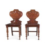 A PAIR OF CARVED MAHOGANY HALL CHAIRS, mid 19th century, with shaped back with scroll back cresting,