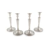 A SET OF FOUR GEORGE III NEO-CLASSICAL SILVER CANDLESTICKS, London 1785, mark of John Wakelin &