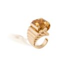 A CITRINE AND GOLD RETRO RING, CIRCA 1940The rectangular-cut citrine within a raised swing-boat