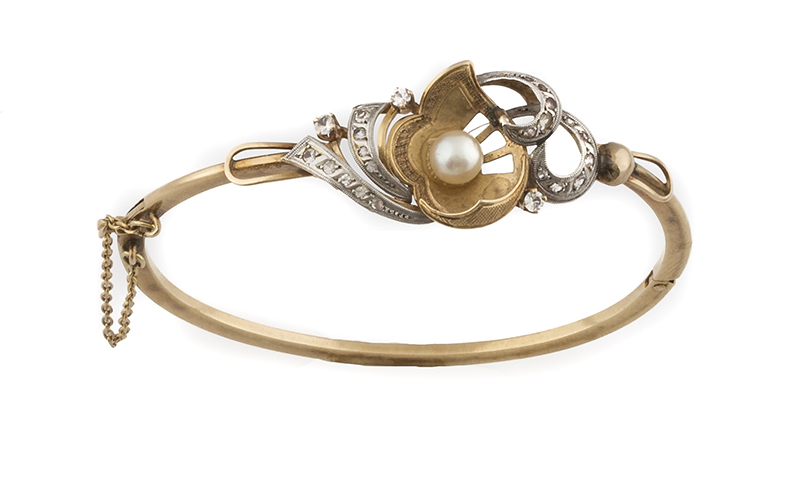 Brazalete rígido con centro de perla entre ondas de zafiros blancos En oro amarillo de 18K. con