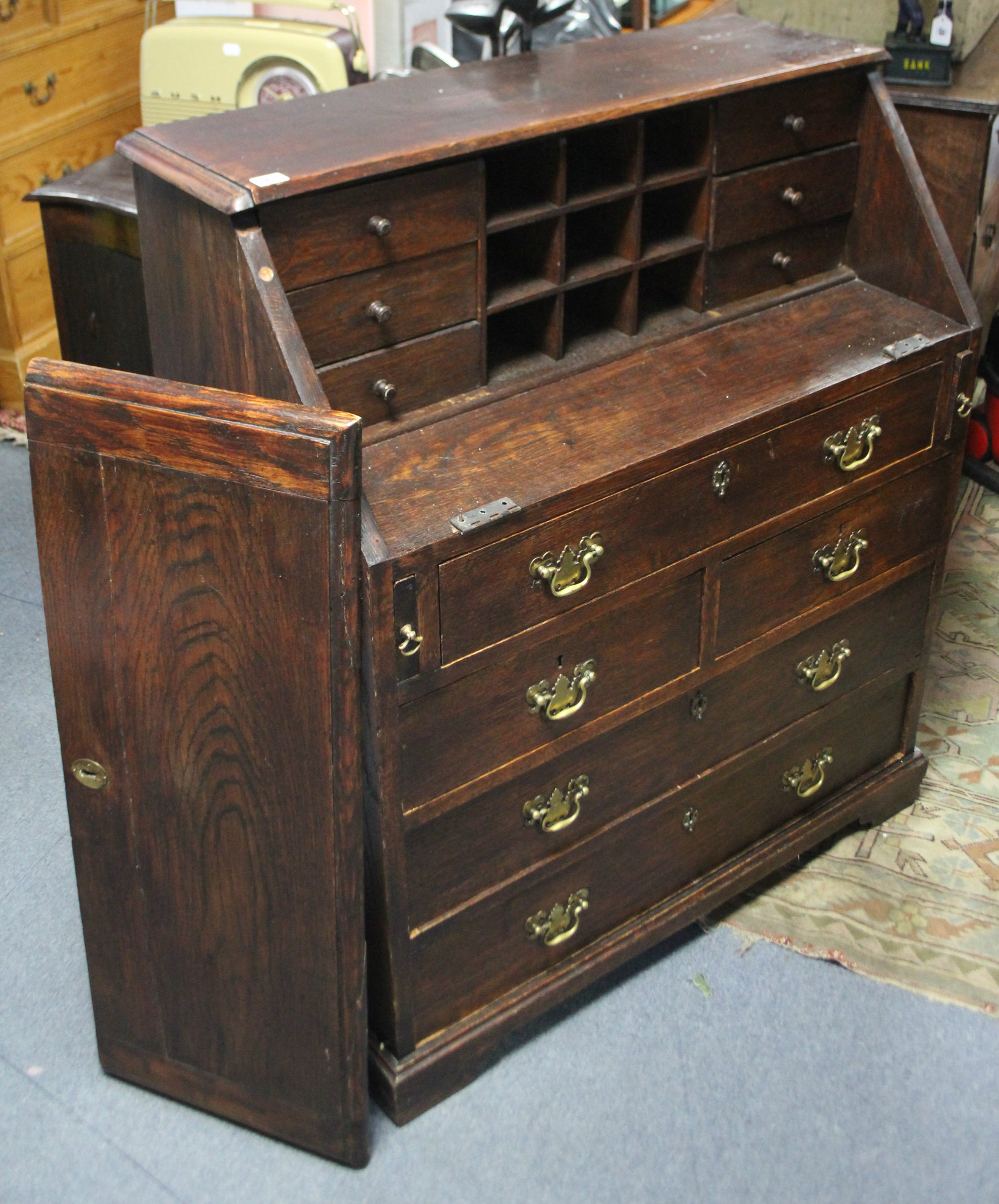 A 19th century oak bureau with fitted interior enclosed by fall-front above an arrangement of