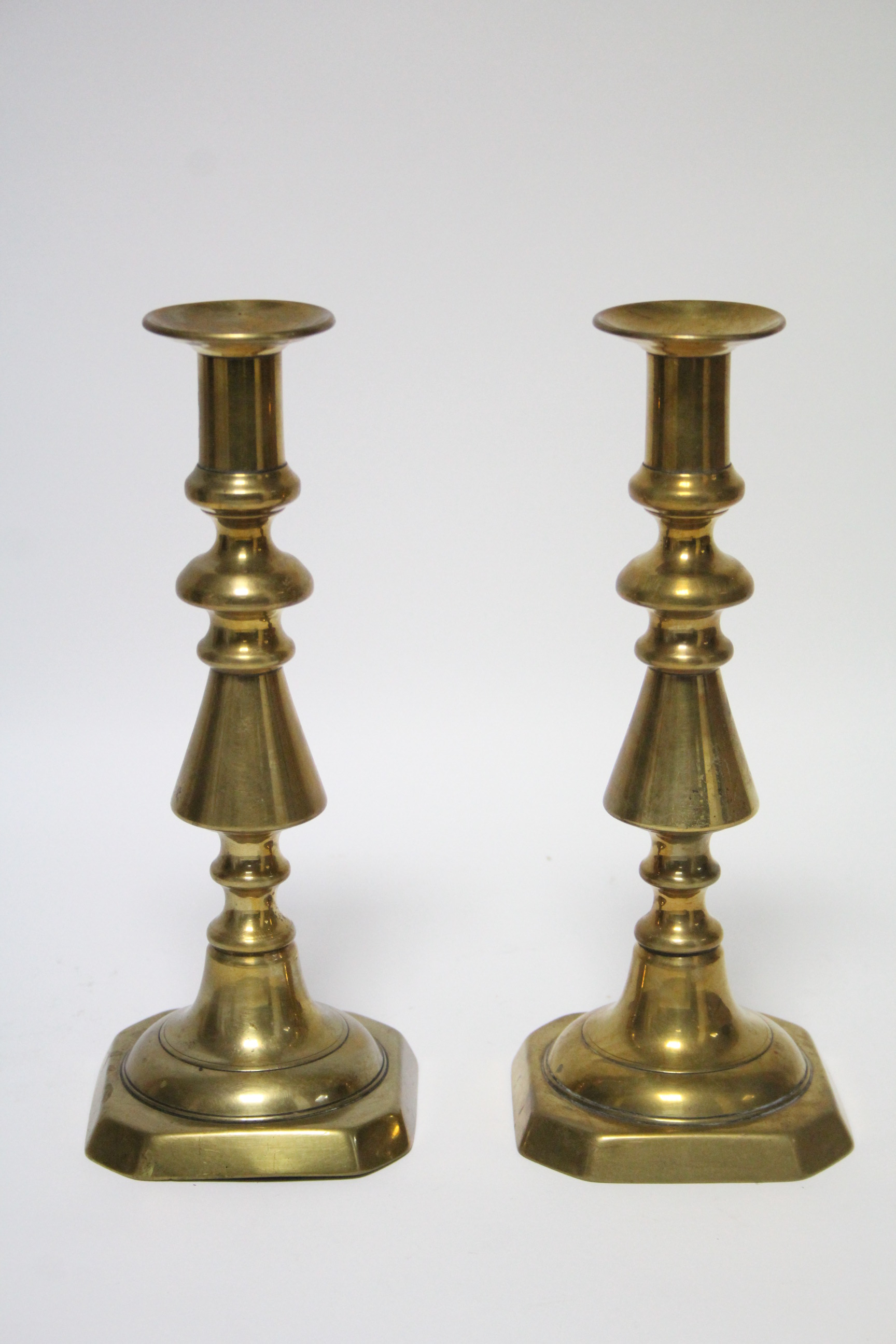 A pair of late 19th/early 20th century brass candlesticks, on turned tapering columns & square