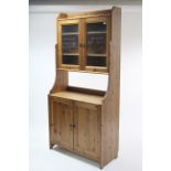 A pine tall standing cabinet, the upper part with two adjustable shelves enclosed by pair of