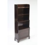 A mahogany small standing bookcase with three open shelves above cupboard enclosed by fielded