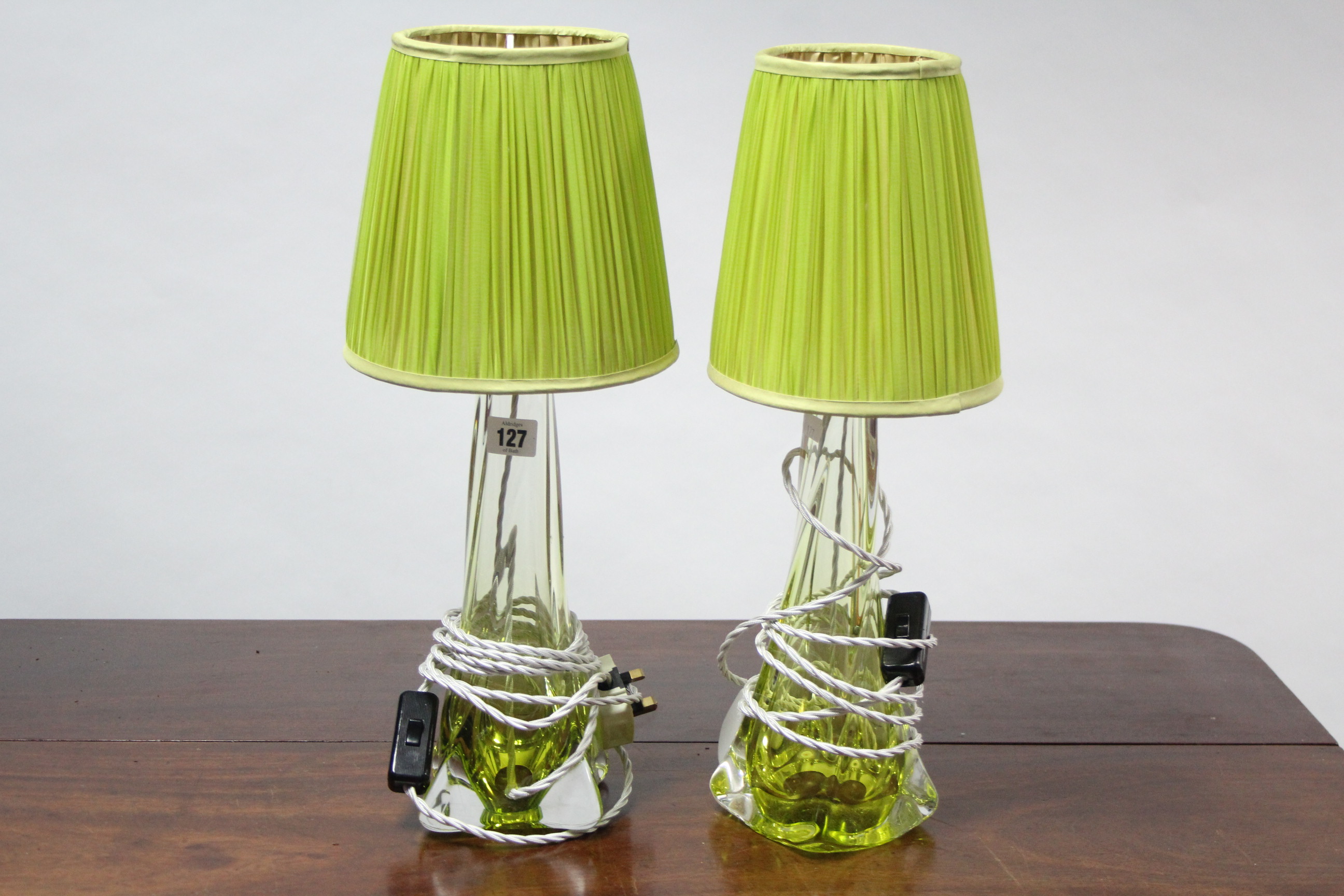 A pair of green tinted glass table lamps, bases of square tapered form, with shades, 16½” high.