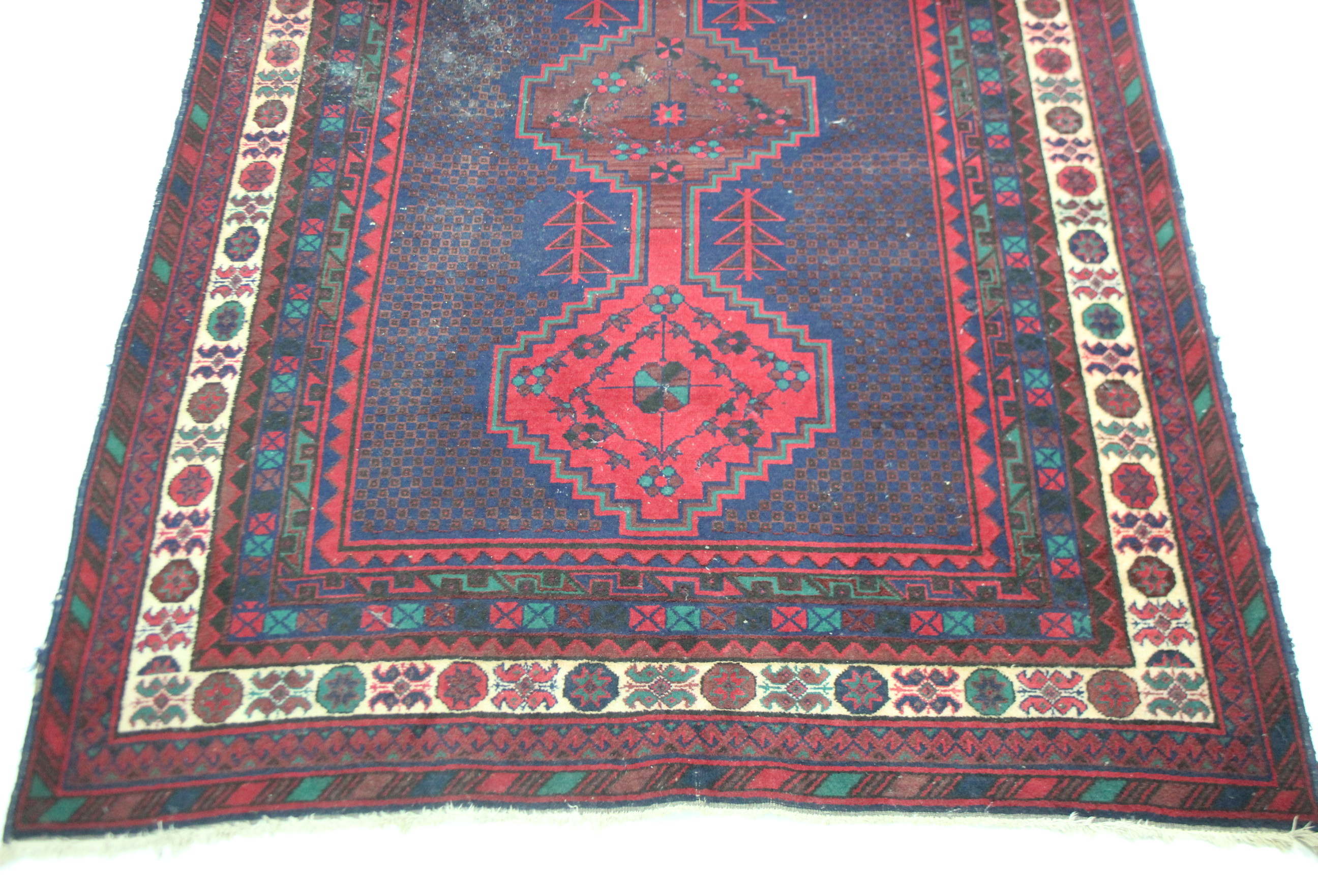 A Persian pattern small carpet of crimson deep blue ground, with geometrical design to centre within