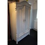 A continental-style white painted pine wardrobe enclosed by pair of panel doors above a long