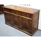 A GOOD QUALITY REPRODUCTION OAK DRESSER BASE, fitted three frieze drawers above cupboard enclosed by