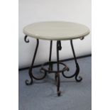 A wrought-metal garden table with four scroll supports, & with simulated marble top, 31” diameter.