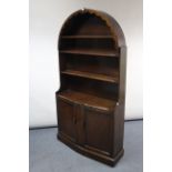 An oak dresser with domed top, fitted three open shelves above cupboard enclosed by pair of panel