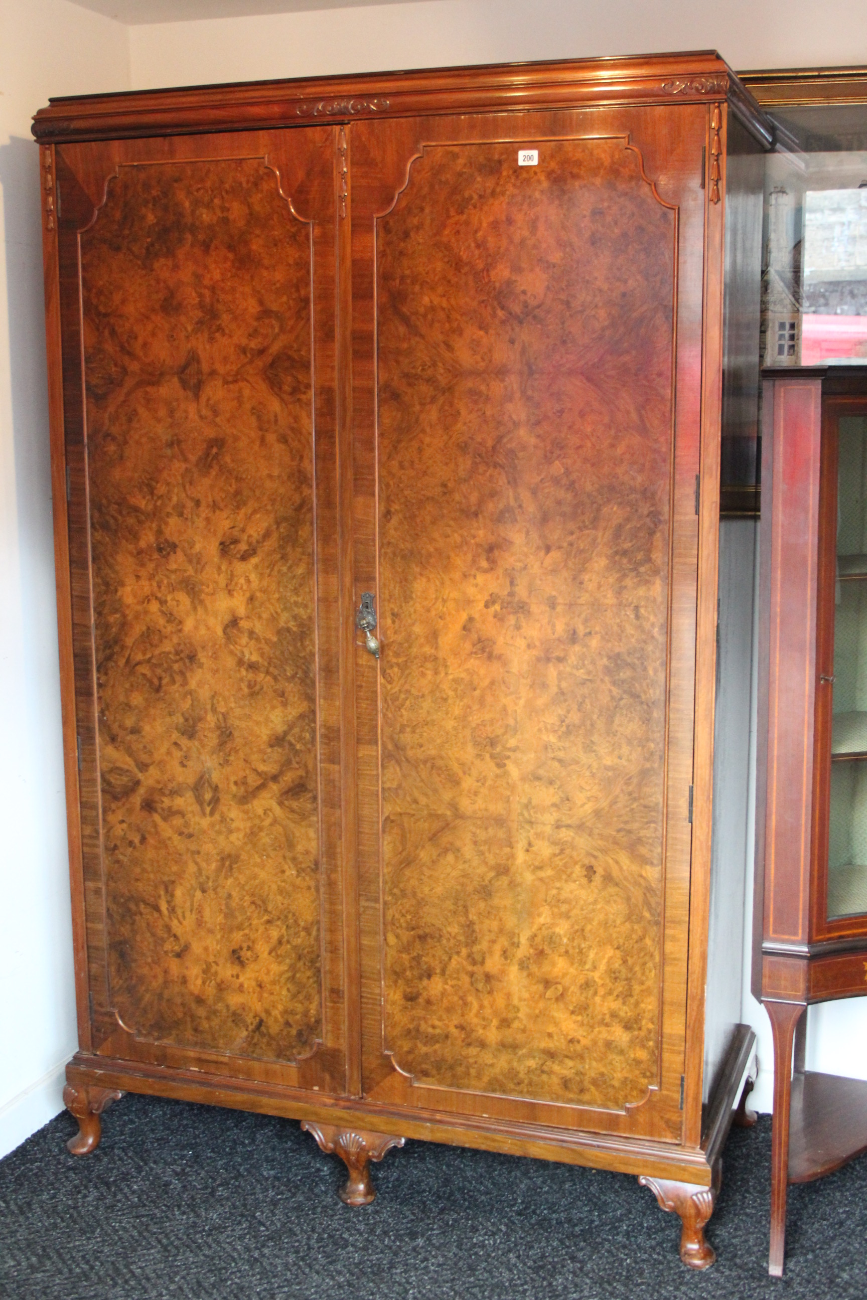 A mid-20th century burr-walnut three-piece bedroom suite comprising a twin-door wardrobe, 48” wide