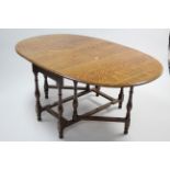 A 1930’s oak oval gate-leg dining table on baluster-turned legs & turned feet with plain stretchers,