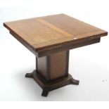 A mid-20th century oak draw-leaf dining table on square centre pedestal, 35¾” x 59½” (open); & a