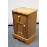 A pine bedside cabinet fitted frieze drawer above cupboard enclosed by panel door, & on shaped