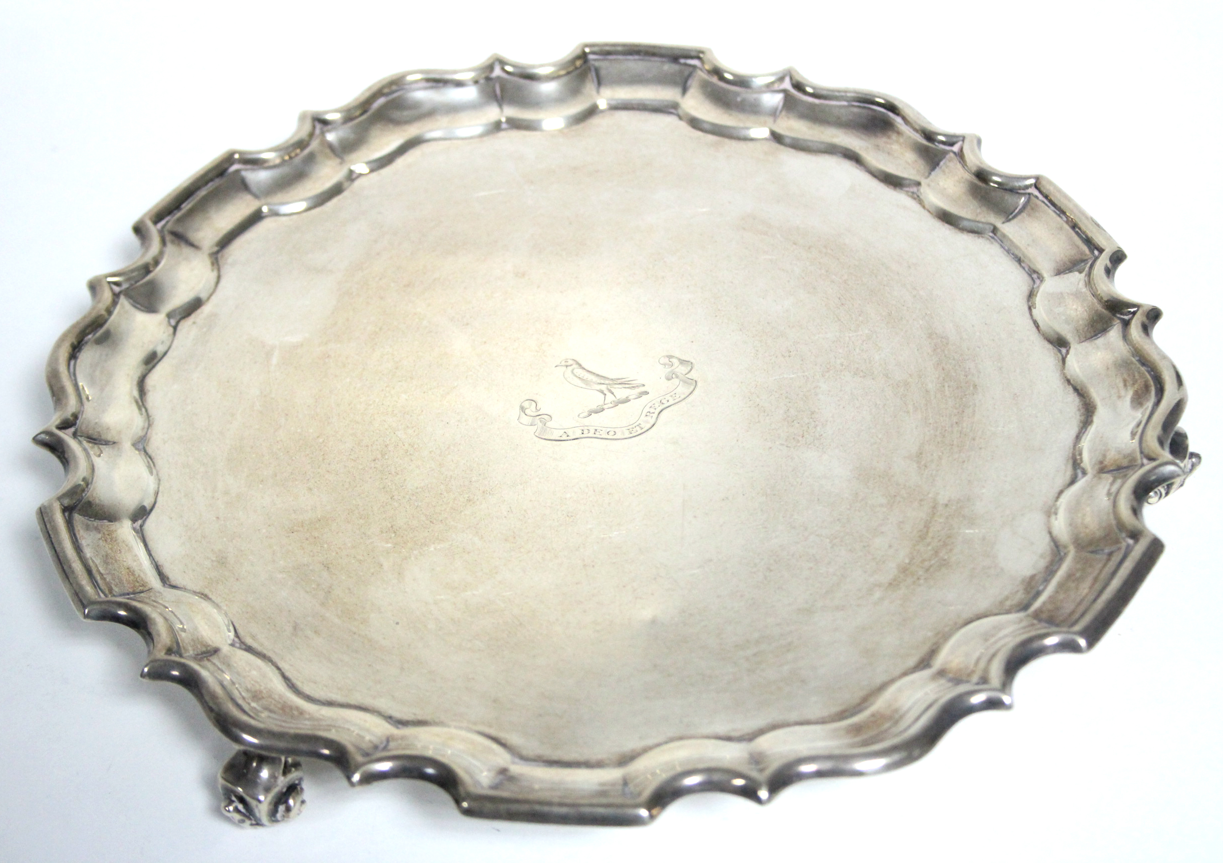 A late Victorian salver with raised pie-crust edge & engraved family crest, on three scroll feet,