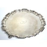 A late Victorian salver with raised pie-crust edge & engraved family crest, on three scroll feet,