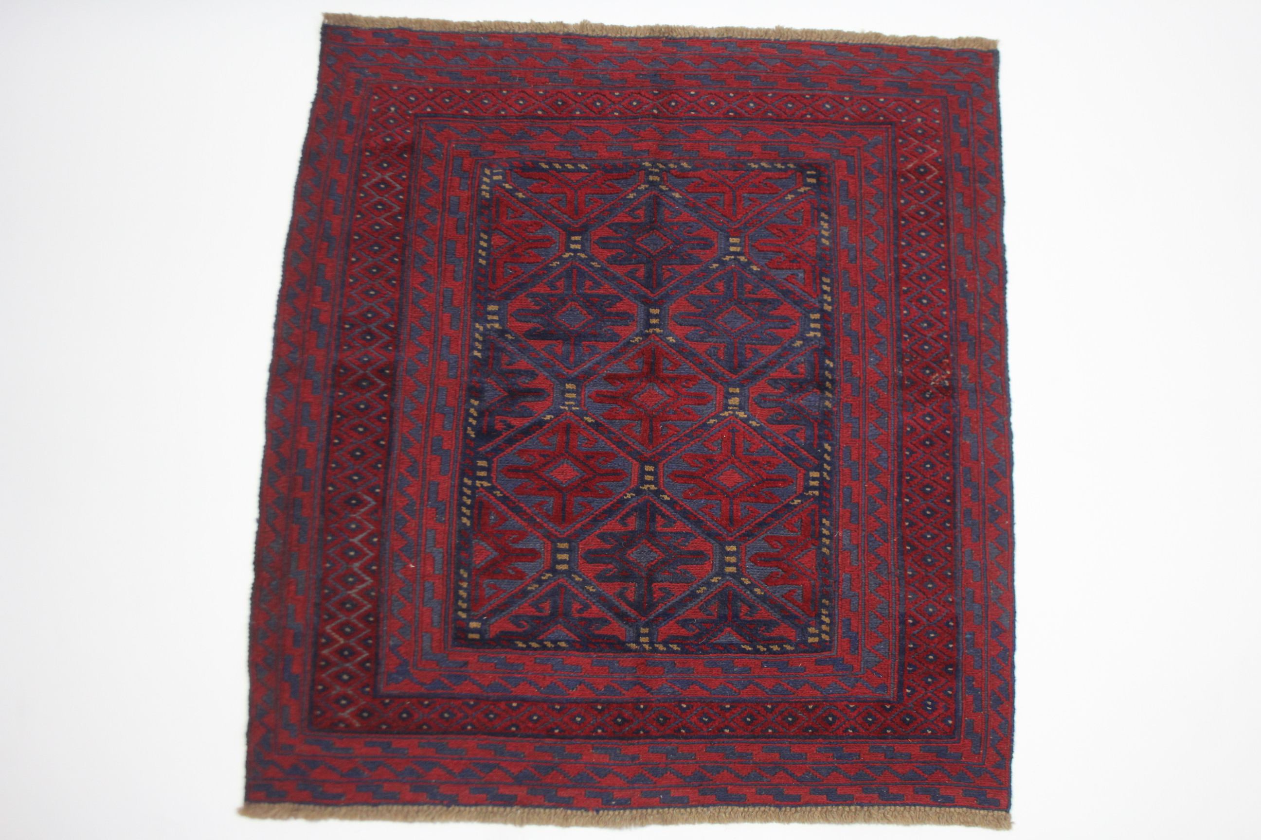 A Kazak rug of crimson, deep blue & ivory ground with geometric lozenge design within multiple