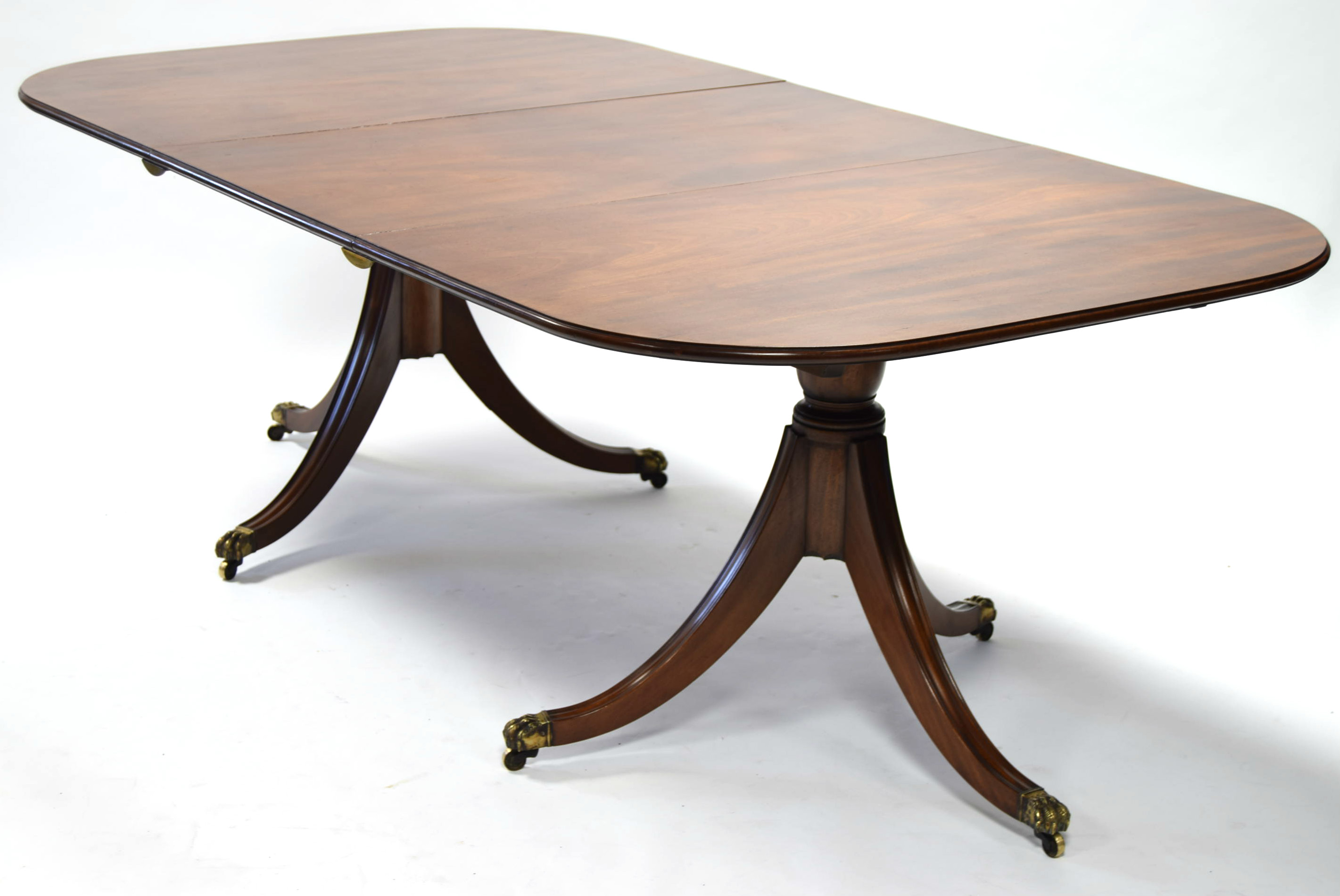 A Regency-style mahogany twin-pedestal dining table, the rectangular top with rounded corners, one