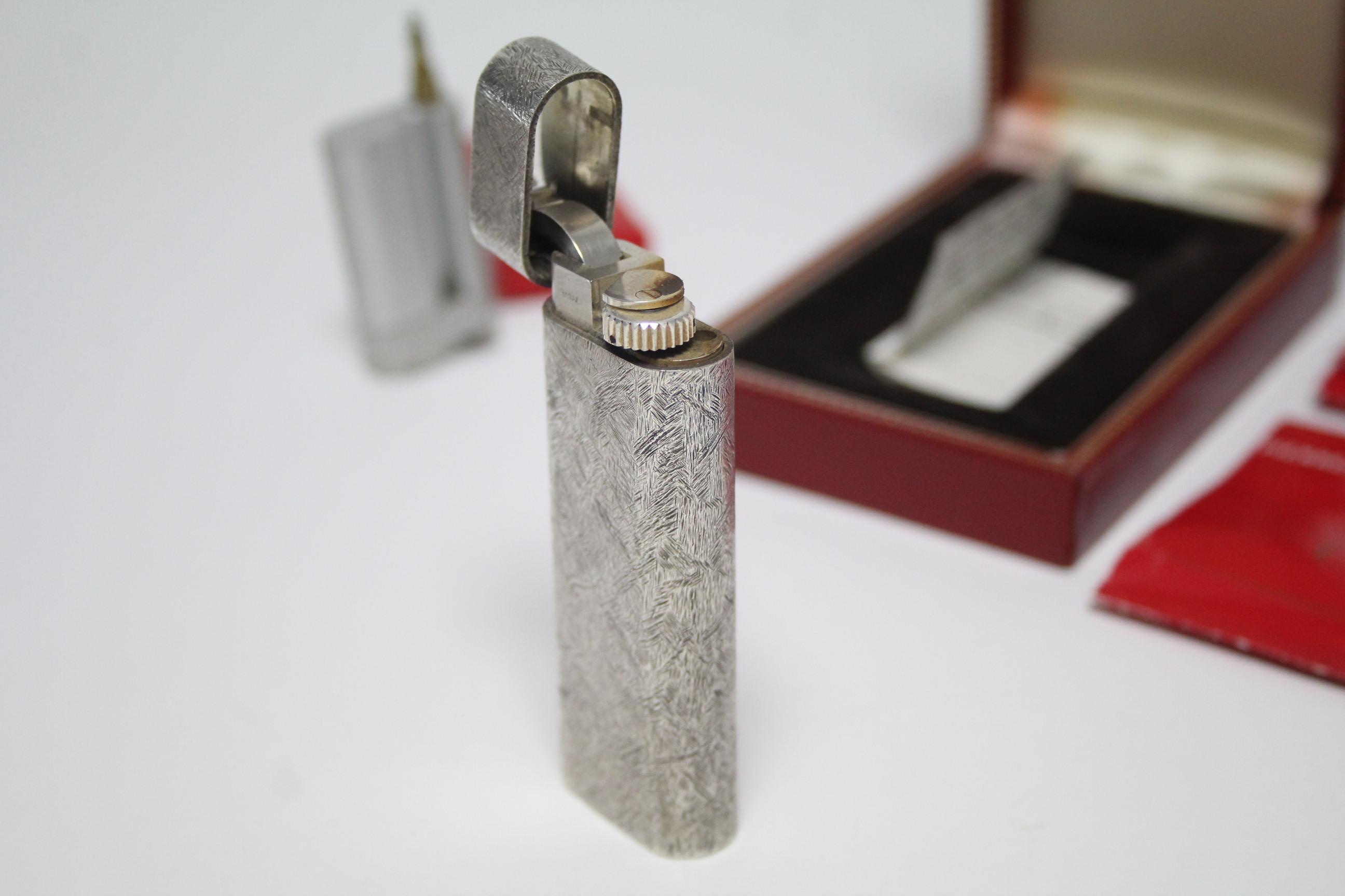 A Cartier pocket cigarette lighter in white metal “Brushed Florentine” case; in original box, with - Image 2 of 4