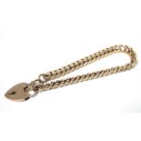 A 9ct. gold curb-link bracelet with padlock clasp & safety chain. (15gm).