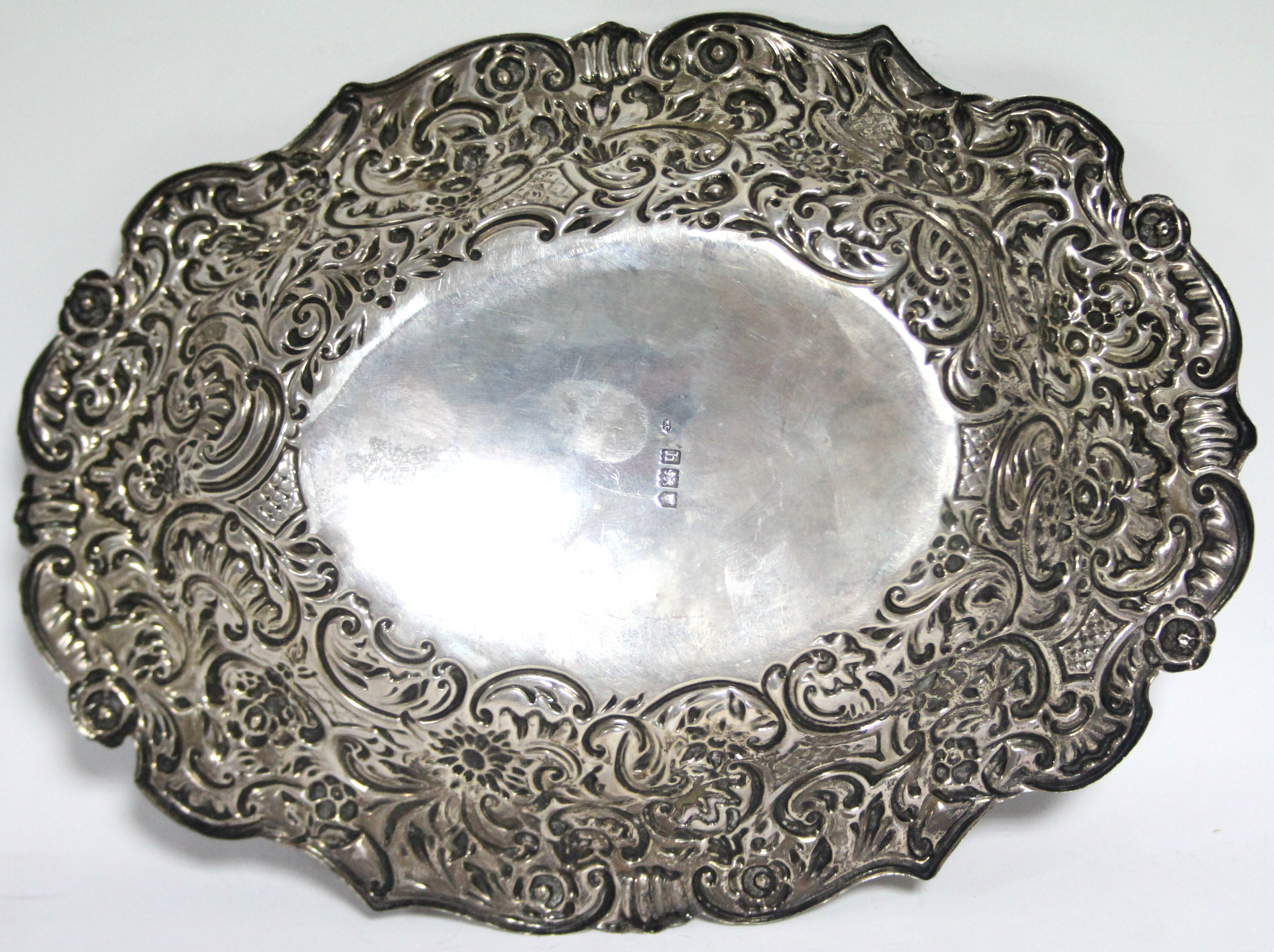An Edwardian oval shallow dish, the wide borders embossed with flowers & scrolls, 10” x 7½”; - Image 3 of 3