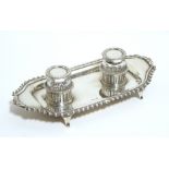 An Edwardian desk inkstand of oblong form, with gadrooned border & fitted two round glass inkwells