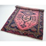 A Persian rug of pink ground, dark blue figured with central lozenge, 7’ 5” x 4’ 7”; & a similar