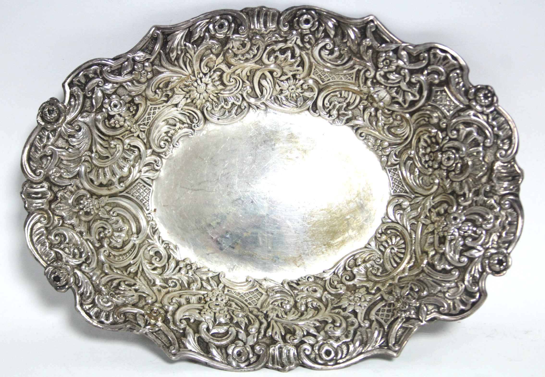 An Edwardian oval shallow dish, the wide borders embossed with flowers & scrolls, 10” x 7½”; - Image 2 of 3