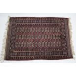 A Bokhara rug of crimson, deep blue, & ivory ground, with three rows of sixteen guhls within