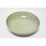 A Ruskin pottery circular shallow bowl with iridescent glaze over a mottled green/blue ground,