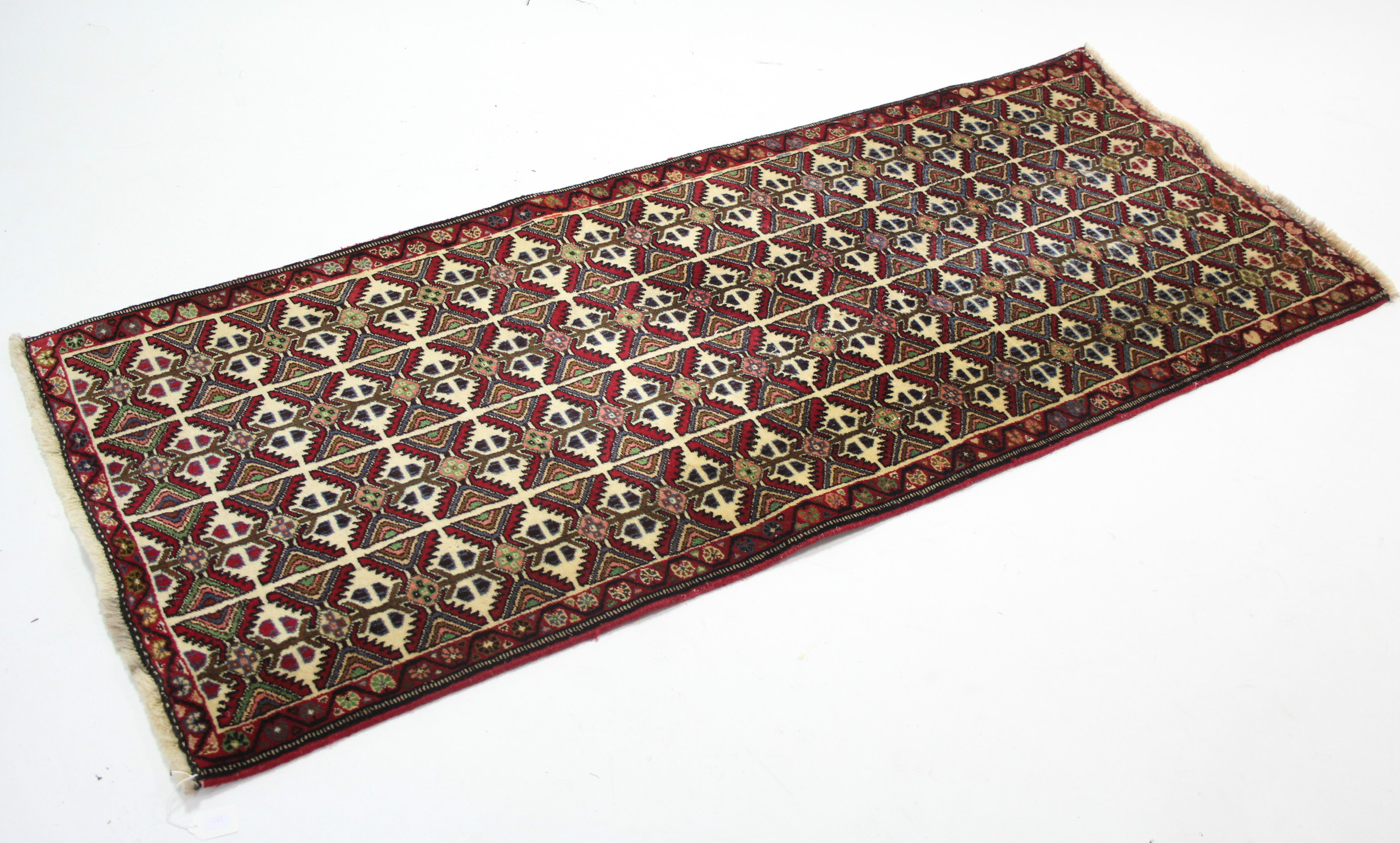 A modern Persian rug of ivory ground with all-over repeating multi-coloured geometric pattern; 6’ 2”