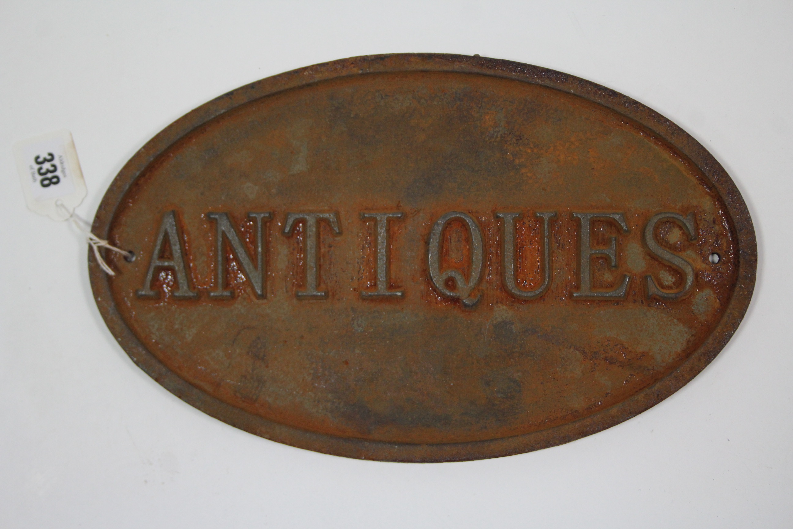 A reproduction cast-iron oval sign "ANTIQUES", 8¼" x 13½".