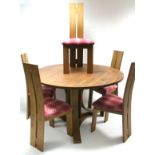 A contemporary wood dining table with circular top & on three shaped supports with triform base