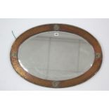 An Arts & Crafts copper frame oval wall mirror with reeded edge & raised brass motifs to border, &