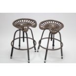 A pair of modern cast-iron tractor-seat swivel stools