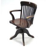 An Edwardian lath-back swivel office chair with hard seat, & on sprung base & four cabriole legs.