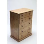 A pine small upright chest fitted five long graduated drawers with turned knob handles, & on