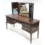 A Stag “Minstrel” mahogany finish kneehole dressing table with triple panel mirror to back, fitted