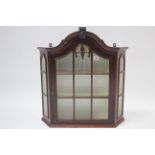 A mahogany wall cabinet with rounded top, fitted two shelves enclosed by glazed door & with glazed