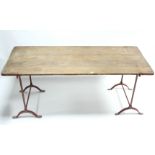 A mid-20th century pine trestle table on red-finish cast-iron end supports, 72” long.