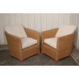 A pair of wicker tub-shaped conservatory chairs, with loose cushions to the seats & backs