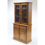 A pine tall cabinet, the upper part with two adjustable shelves enclosed by a pair of leaded