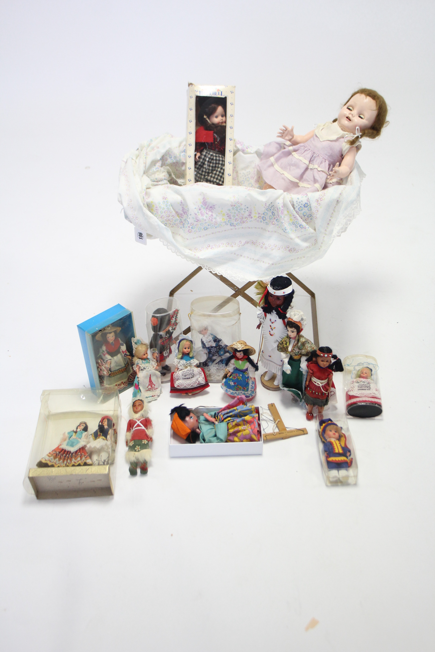 A Pedigree girl doll; a folding doll’s cot; thirteen various costume dolls; & a Pelham string