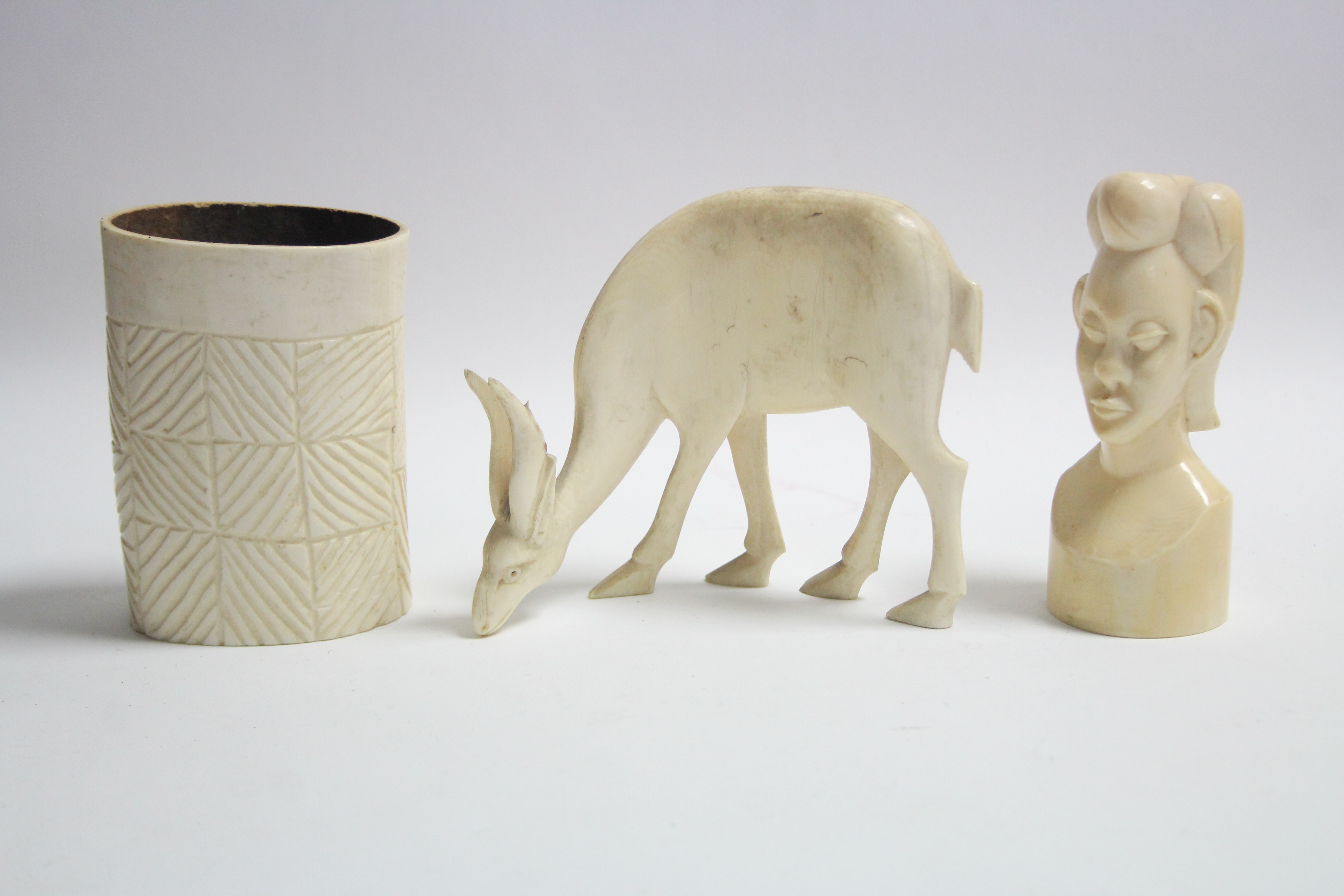 A carved ivory bust, 4½” high; a ditto antelope model, 4½” high; & an ivory spill vase, 4” high.