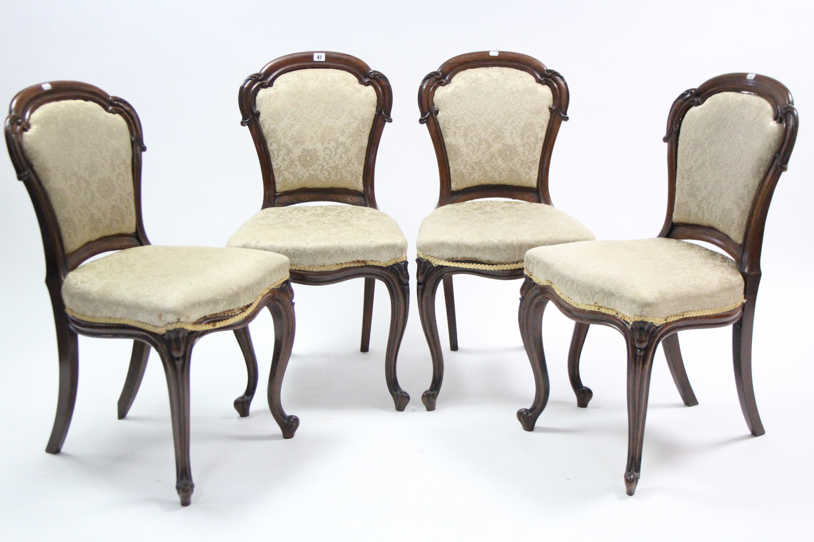 A set of four Victorian carved rosewood dining chairs, the padded balloon-backs & seats